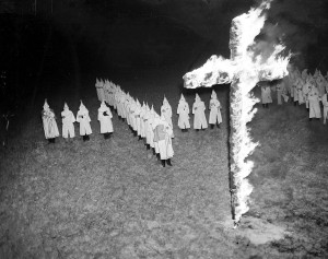 FILE - In this Jan. 30, 1939 file photo, members of the Ku Klux Klan, wearing white hoods and robes, watch a burning cross in Tampa, Fla. In 2016, KKK leaflets have shown up in suburban neighborhoods from the Deep South to the Northeast. (AP Photo/File)